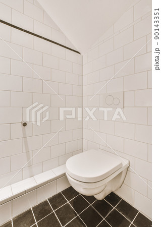 Bathroom interior with a toilet, white tiles on the walls and black on the floor in a modern house Bathroom interior with a toilet, white tiles on the walls and black on the floor in a modern house 90143351