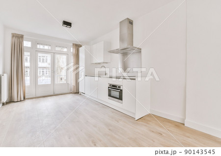 Spacious empty bright room with a corner kitchen in white in a modern house 90143545