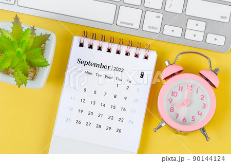 September 2022 desk calendar and pink alarm clock on yellow background. September 2022 desk calendar and pink alarm clock on yellow background. 90144124