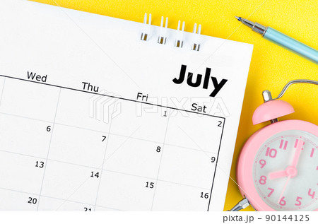 July 2022 desk calendar and pen with plant pot on yellow background. 90144125