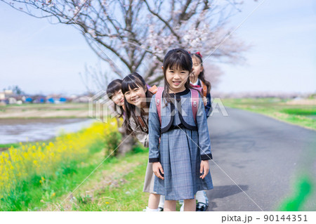 登下校中に通学路で遊ぶ小学生の女の子たち 90144351