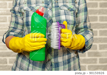 Woman in protective glove with bottle of detergent. Woman in protective glove with bottle of detergent. 90150926