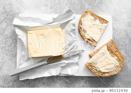 Block of butter with butter knife in a open pack.  Buttering bread 90152430