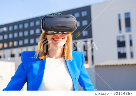 Woman with VR virtual reality goggles experiences a metaverse world. Augmented reality technology concept Woman with VR virtual reality goggles experiences a metaverse world. Augmented reality technology concept 90154867
