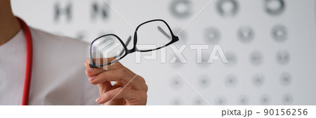 Woman doctor ophthalmologist shows glasses, close-up, blurry Woman doctor ophthalmologist shows glasses, close-up, blurry 90156256