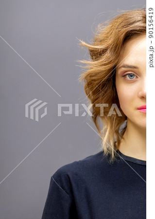 Portrait of a beautiful young caucasian red-haired woman with short wavy hairstyle smiling and looking at camera on dark gray background with copy space 90156419