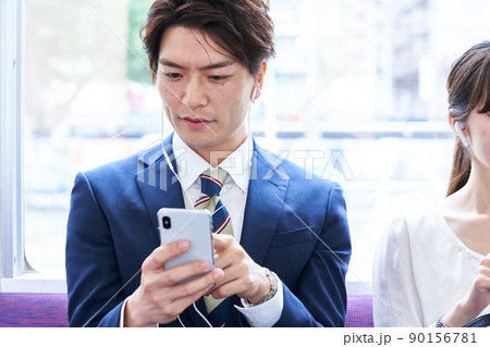 電車内でスマホを見るスーツ姿の男性　撮影協力「京王電鉄株式会社」 90156781