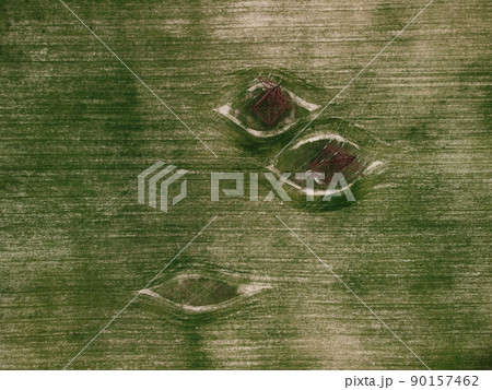Aerial view on Green wheat field with power pylons in countryside. Field of wheat blowing in the wind on sunset. Ears of barley crop in nature. Agronomy, industry and food production. Aerial view on Green wheat field with power pylons in countryside. Field of wheat blowing in the wind on sunset. Ears of barley crop in nature. Agronomy, industry and food production. 90157462