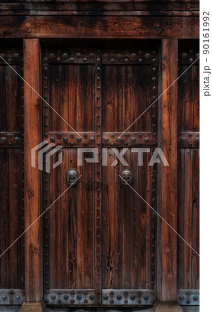 Closeup of dark wooden door with metallic brass vintage lion handles and decor for your design. Retro vintage style. Copy space. Textured background. 90161992