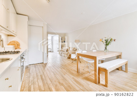 Contemporary open plan kitchen with dining table set and gray sofa in light spacious room Contemporary open plan kitchen with dining table set and gray sofa in light spacious room 90162822