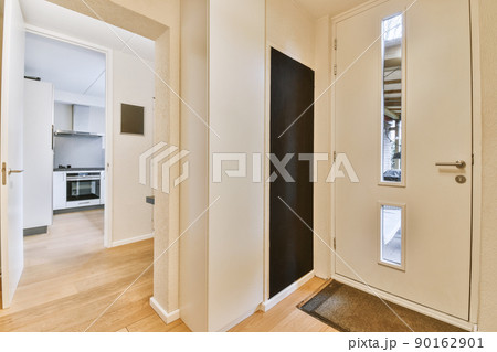 Narrow corridor with white walls and door leading to kitchen with parquet floor in modern apartment Narrow corridor with white walls and door leading to kitchen with parquet floor in modern apartment 90162901