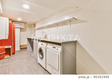 A small laundry room with appropriate appliances indoors in a modern residential apartment 90162990
