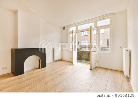 Interior of spacious light room with fireplace and elegant chandelier against balcony door and windows Interior of spacious light room with fireplace and elegant chandelier against balcony door and windows 90163129