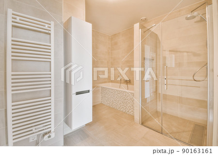 Sinks with mirrors and shower box with glass door in modern bathroom with white tiled walls Sinks with mirrors and shower box with glass door in modern bathroom with white tiled walls 90163161