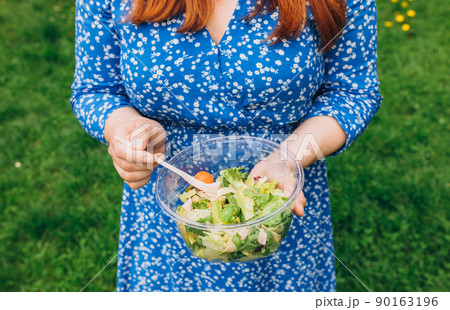 Hand of woman holding bowl with salad over isolated nature background. Healthy picnic, food banner 90163196