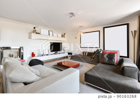 Lovely large living room with low upholstered sofas and a small red coffee table 90163268