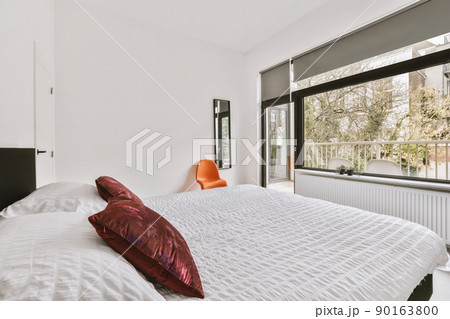 The interior of a modern bedroom in a minimalist style with access to a balcony in a cozy house 90163800