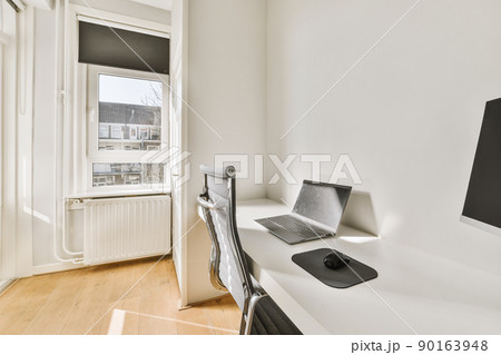 Comfortable chair placed near desk with computer monitors and whiteboard in light workplace in modern apartment 90163948
