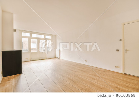 Interior of spacious light room with fireplace and elegant chandelier against balcony door and windows Interior of spacious light room with fireplace and elegant chandelier against balcony door and windows 90163969