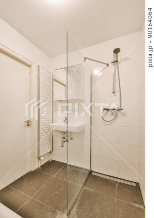 Sinks with mirrors and clean bathtub located near shower box with glass door in modern bathroom with white tiled walls 90164064