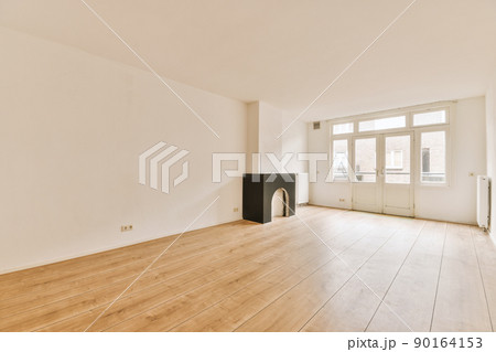 Interior of spacious light room with fireplace and elegant chandelier against balcony door and windows Interior of spacious light room with fireplace and elegant chandelier against balcony door and windows 90164153