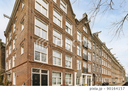 The corner view of brick buildings with signs, cars, pavement and wooden doors lead to the apartment The corner view of brick buildings with signs, cars, pavement and wooden doors lead to the apartment 90164157
