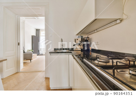 Kitchen in a modern house with white cabinets and appliances in metal color 90164351