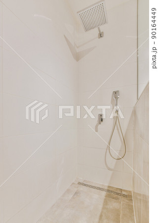 Shower faucets attached to tiled wall near glass partition and ornamental curtail in washroom at home Shower faucets attached to tiled wall near glass partition and ornamental curtail in washroom at home 90164449