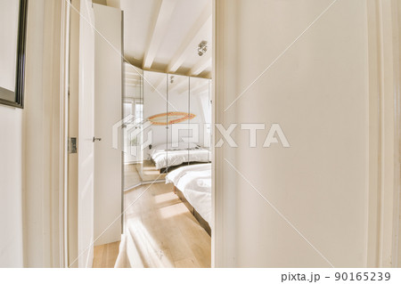 Entrance to a spacious bedroom with a large white bed and a glass wardrobe in a modern house 90165239