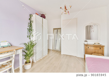 Cozy bedroom with bed located against mirror under the dressing-table with plants near another table and chair 90165945