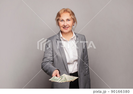 Happy senior business woman holding money us dollars on gray banner background 90166380