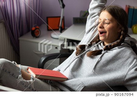A young girl yawns during a break in her school reading. 90167094