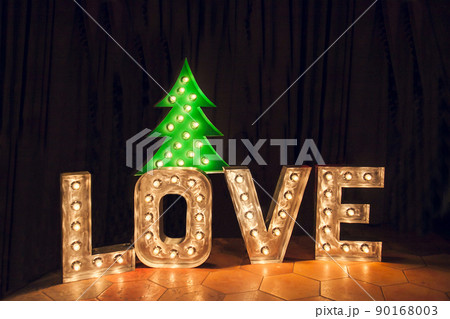 Rust metal letters with electric lights in the word LOVE and a glowing Christmas tree Rust metal letters with electric lights in the word LOVE and a glowing Christmas tree 90168003