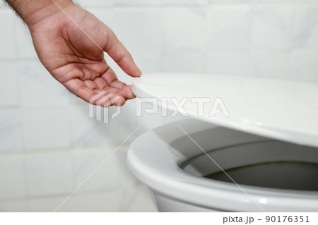 man's hand opening the toilet lid 90176351