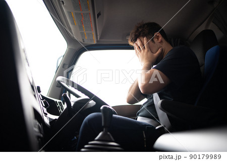 トラックの運転席で頭を抱える男性 90179989