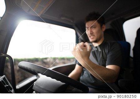 トラックの運転席で拳を握りしめる男性 トラックの運転席で拳を握りしめる男性 90180250