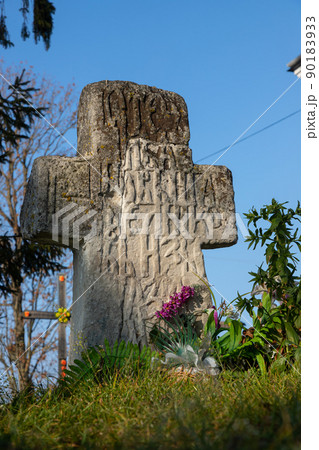 Old stone cross against wall and grass Old stone cross against wall and grass 90183933