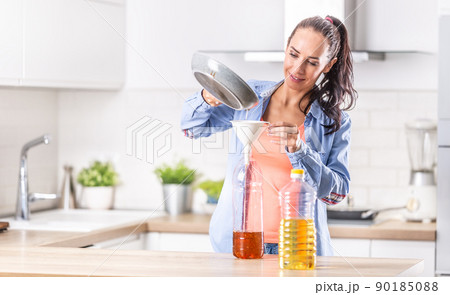 Woman pouring used cooking oil for recycling and reuse into the plastic bottle to be made in the factory into the fuel additive Woman pouring used cooking oil for recycling and reuse into the plastic bottle to be made in the factory into the fuel additive 90185088