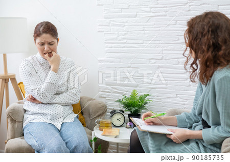 Worried caucasian woman at a session with a psychotherapist.  90185735