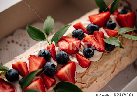 Meringue roll dessert with berries 90186438