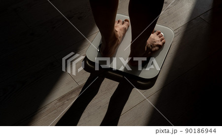 Close-up of female legs on electronic scales. Close-up of female legs on electronic scales. 90186944