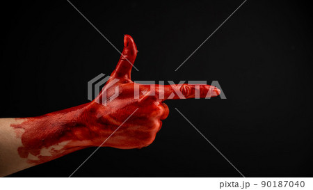 Woman's hand in blood shows a gesture of a gun on a black background. Woman's hand in blood shows a gesture of a gun on a black background. 90187040