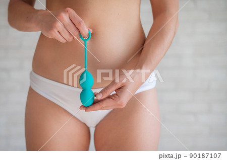 Faceless woman in white panties holding the Kegel trainer for strengthening the intimate muscles of the vagina. Vaginal balls with a displaced center of gravity of a mint color. Sex toy. Faceless woman in white panties holding the Kegel trainer for strengthening the intimate muscles of the vagina. Vaginal balls with a displaced center of gravity of a mint color. Sex toy. 90187107