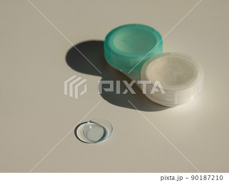 Contact lenses and a storage container on a white table. Contact lenses and a storage container on a white table. 90187210