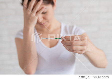 A frustrated woman shows a negative pregnancy test. The concept of female infertility. Human chorionic gonadotropin. One strip. Unjustified expectations. 90187229
