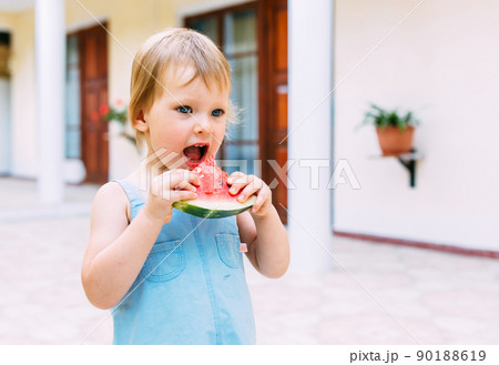 Little cute cheerful girl eating a slice of watermelon close up. Little cute cheerful girl eating a slice of watermelon close up. 90188619