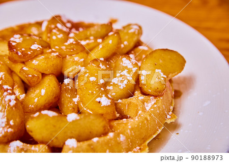 Mouth-watering waffle covered in syrup apple slices and powdered sugar Mouth-watering waffle covered in syrup apple slices and powdered sugar 90188973