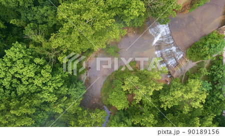 Aerial looking down at cascading waterfalls in river surrounded by green forest Aerial looking down at cascading waterfalls in river surrounded by green forest 90189156