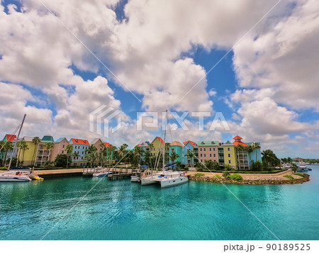 Boats and dock in tropics with colorful buildings and cloudy sky Boats and dock in tropics with colorful buildings and cloudy sky 90189525
