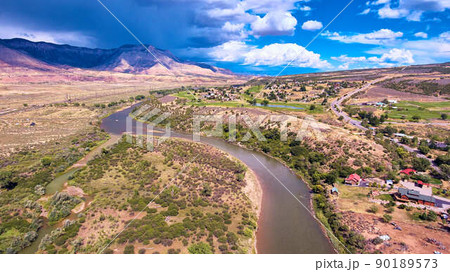 River cutting through the desert with mountains and storm 90189573